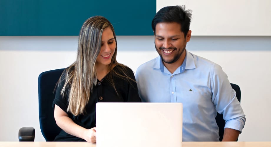 Fotos dos sócios Paula Fernandes e Daniel Huanchicay sorrindo, olhando notebook